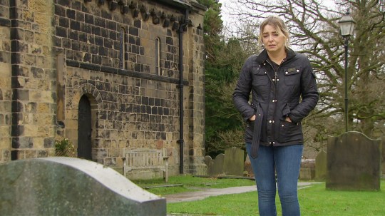 Charity looks at a headstone in Emmerdale