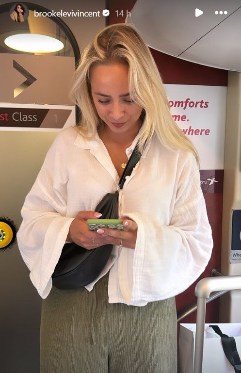 Sacha Parkinson from Coronation Street looking at her phone on a train
